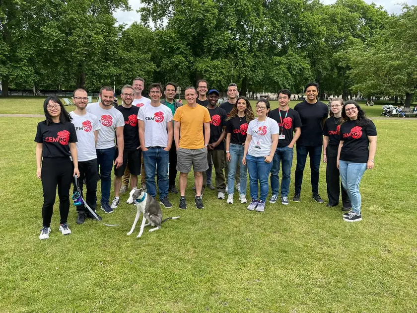 The group standing on grass in a park, most in CEMRG shirts, with a whippet