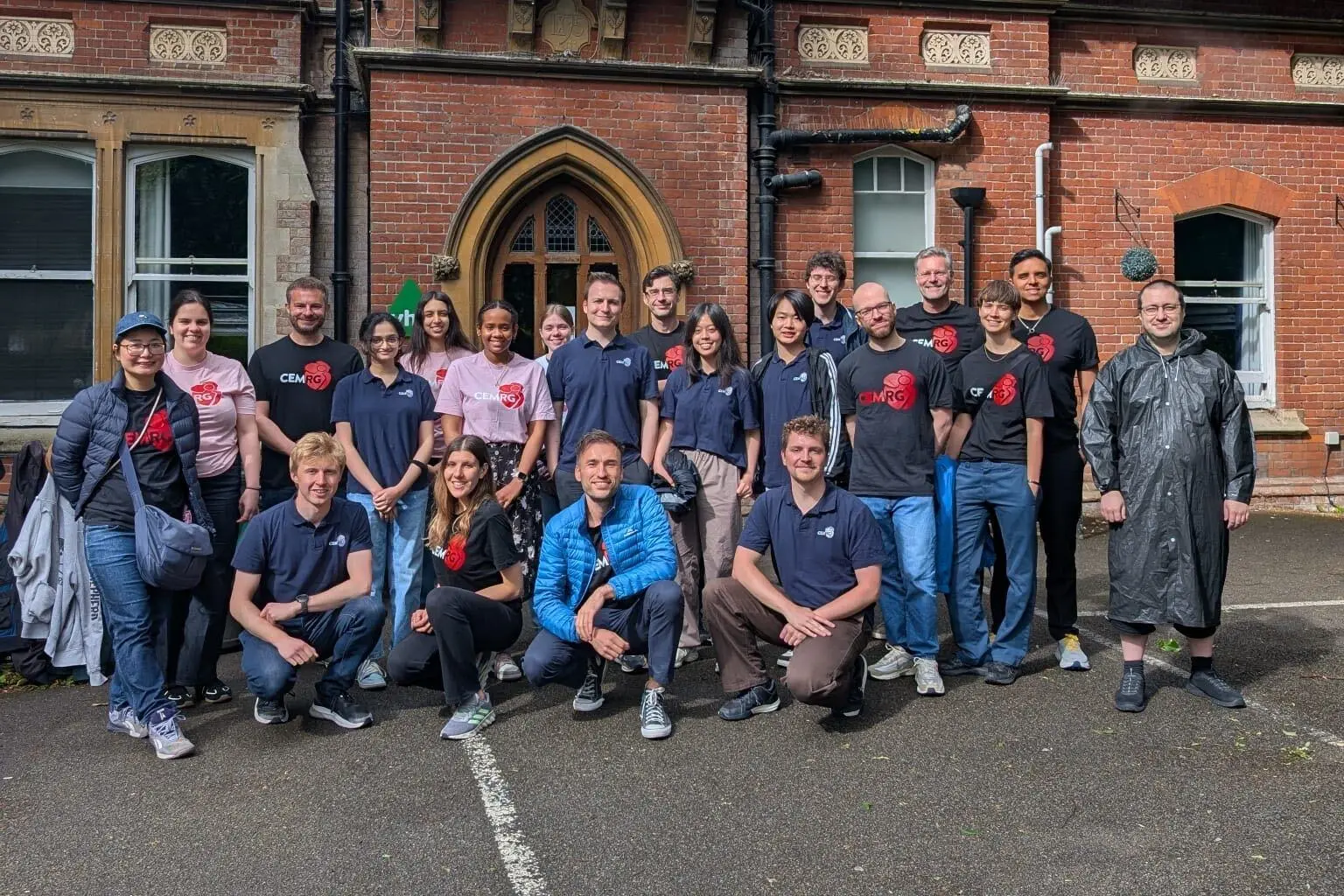 The group standing outside a red-brick building, most in CEMRG shirts
